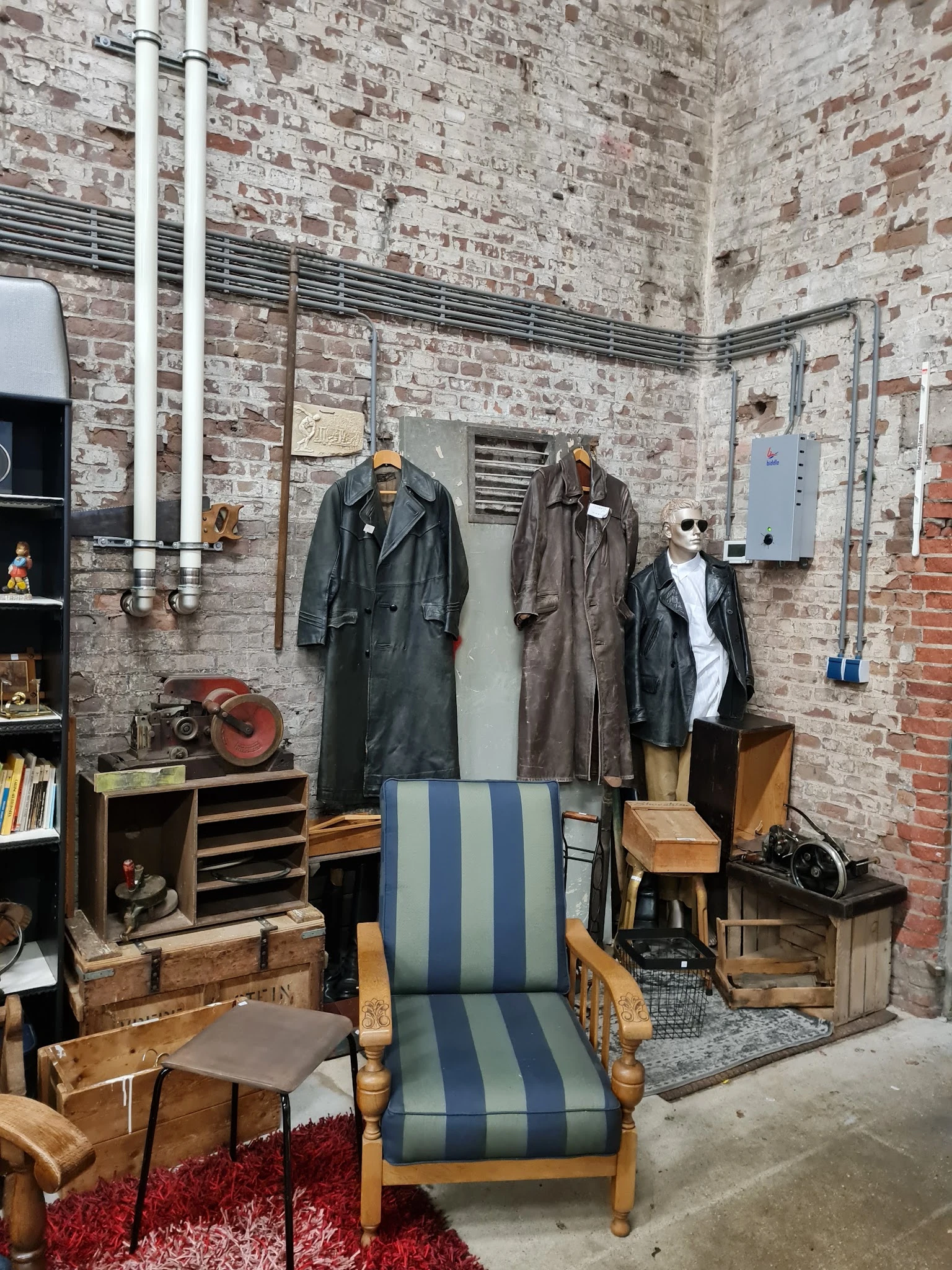 Uitgestalde tweedehands leren jassen en vintage kledingstukken aan hangers in een kringloopwinkel