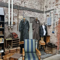 Uitgestalde tweedehands leren jassen en vintage kledingstukken aan hangers in een kringloopwinkel