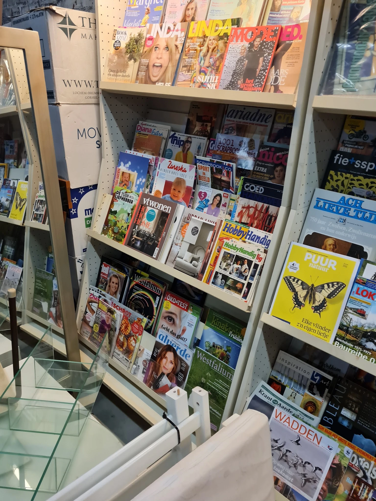 Stellingwand met uitgestalde tijdschriften, magazines en boeken in verschillende talen