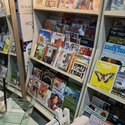 Stellingwand met uitgestalde tijdschriften, magazines en boeken in verschillende talen