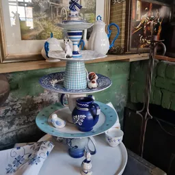 Decoratief serviesgoed gestapeld op een blauw-wit serveerstandaard met onderzetters
