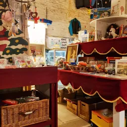 Winkelinterieur met rode tonelkasten vol spullen, decoraties en speelgoed