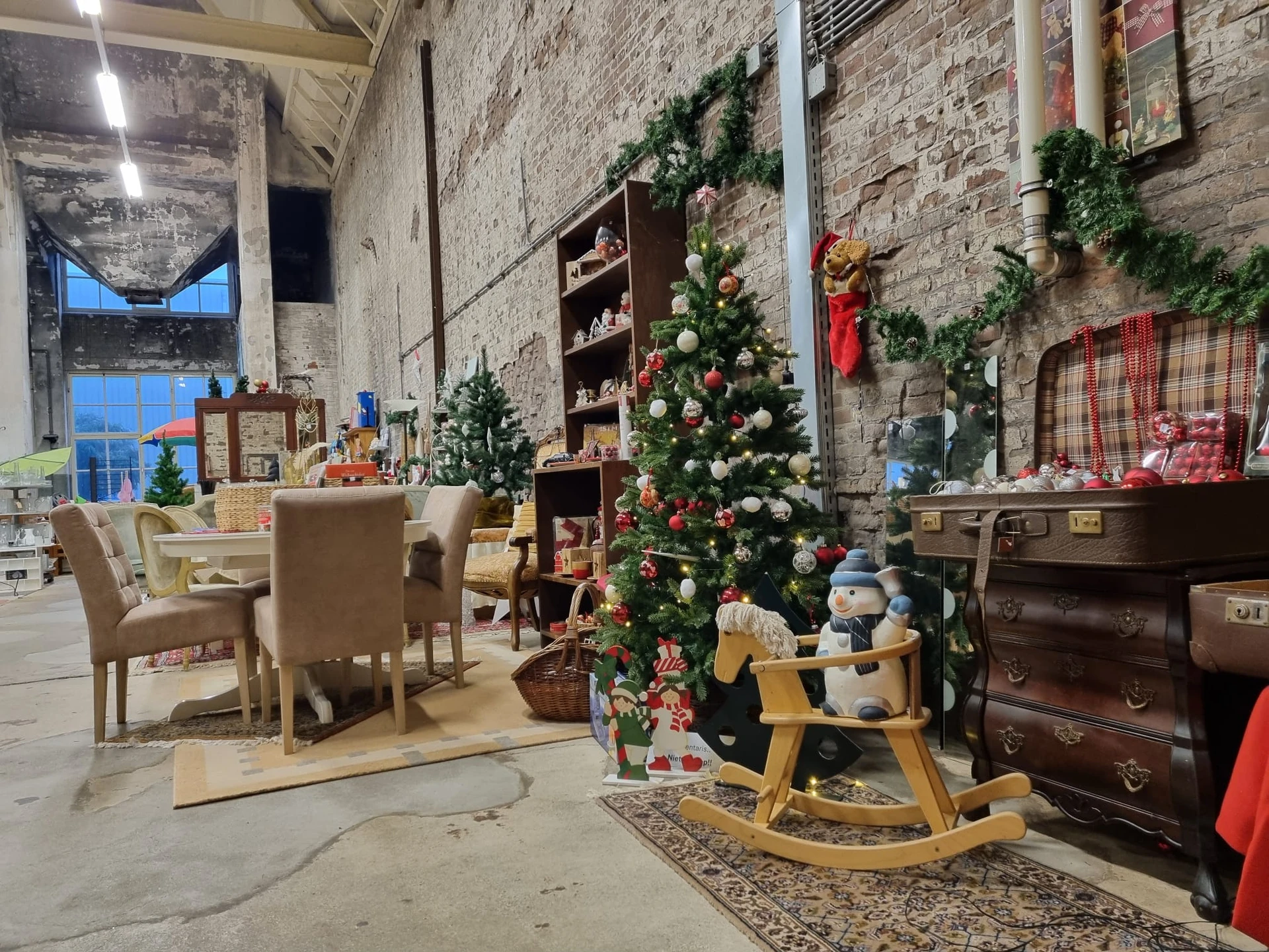 Interieur van kringloopwinkel met kerstdecoratie, meubilair en vintage spullen uitgestald