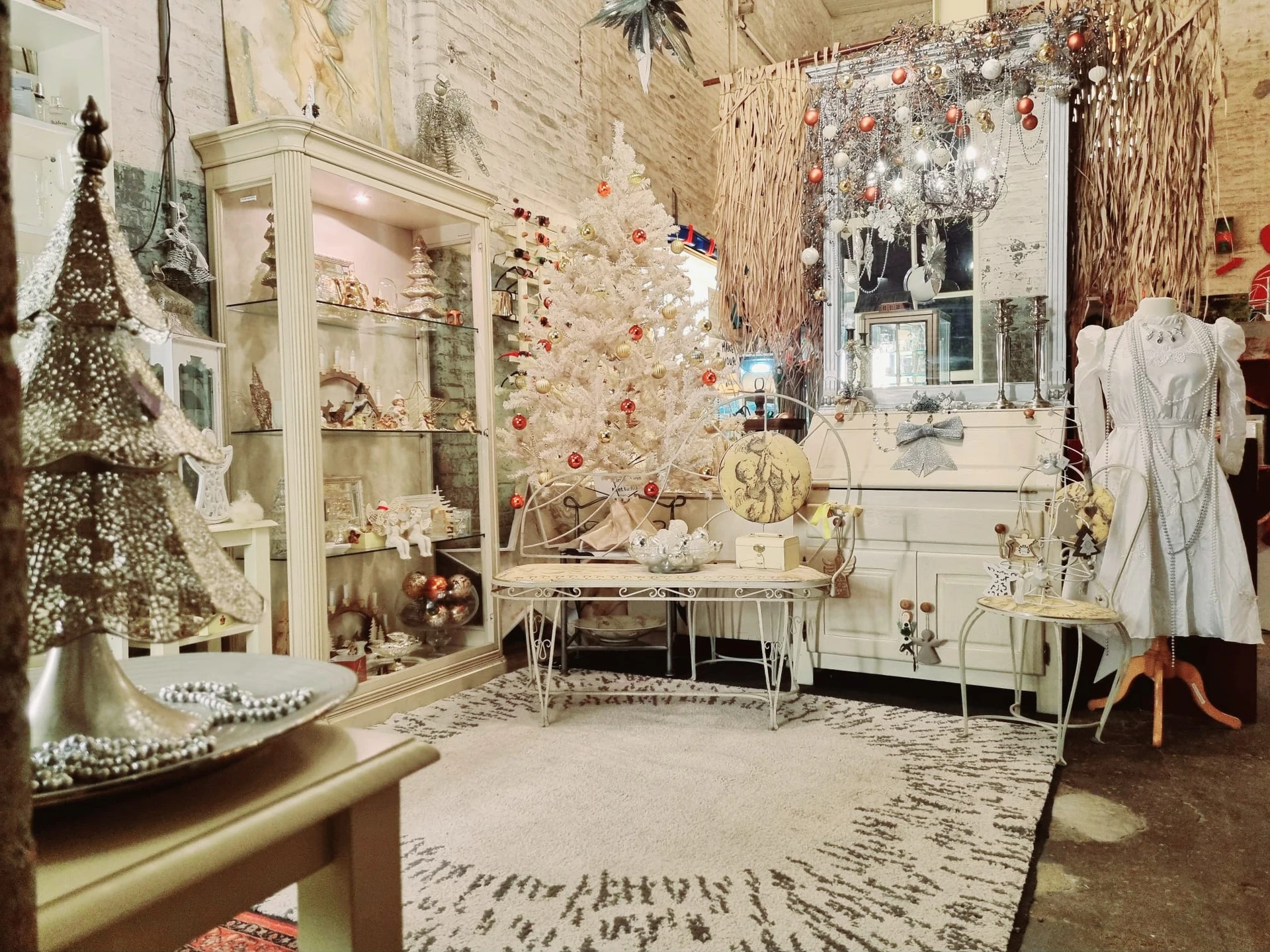 Kerstdecoratie en winkelinrichting met witte kast, kerstboom, sieraden en kledingrek in de kringloopwinkel