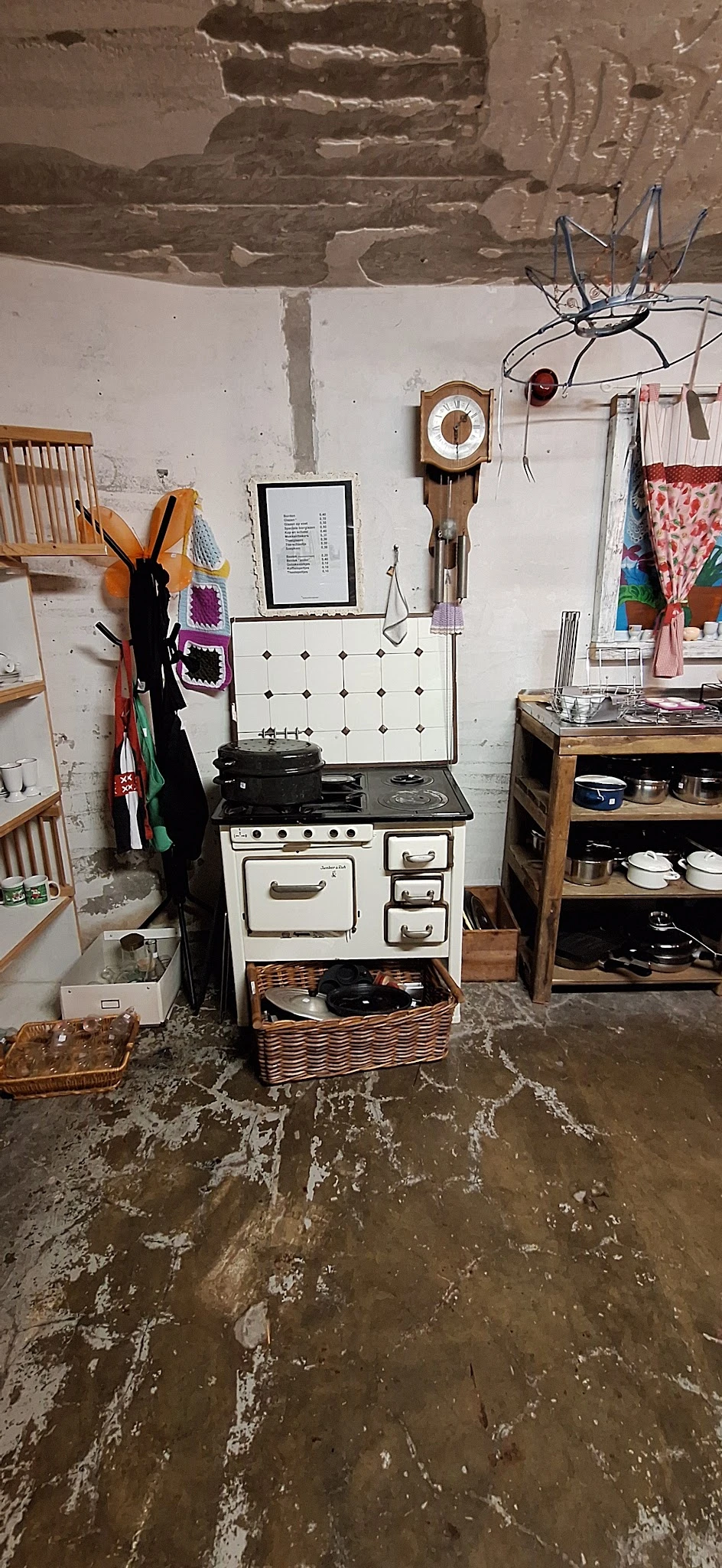 Vintage fornuis en keukengerei uitgestald in kringloopwinkel met stellingen vol kookartikelen