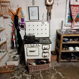 Vintage fornuis en keukengerei uitgestald in kringloopwinkel met stellingen vol kookartikelen