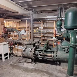 Werkplaats met oude groene industriële machines en stellingen vol met voorwerpen