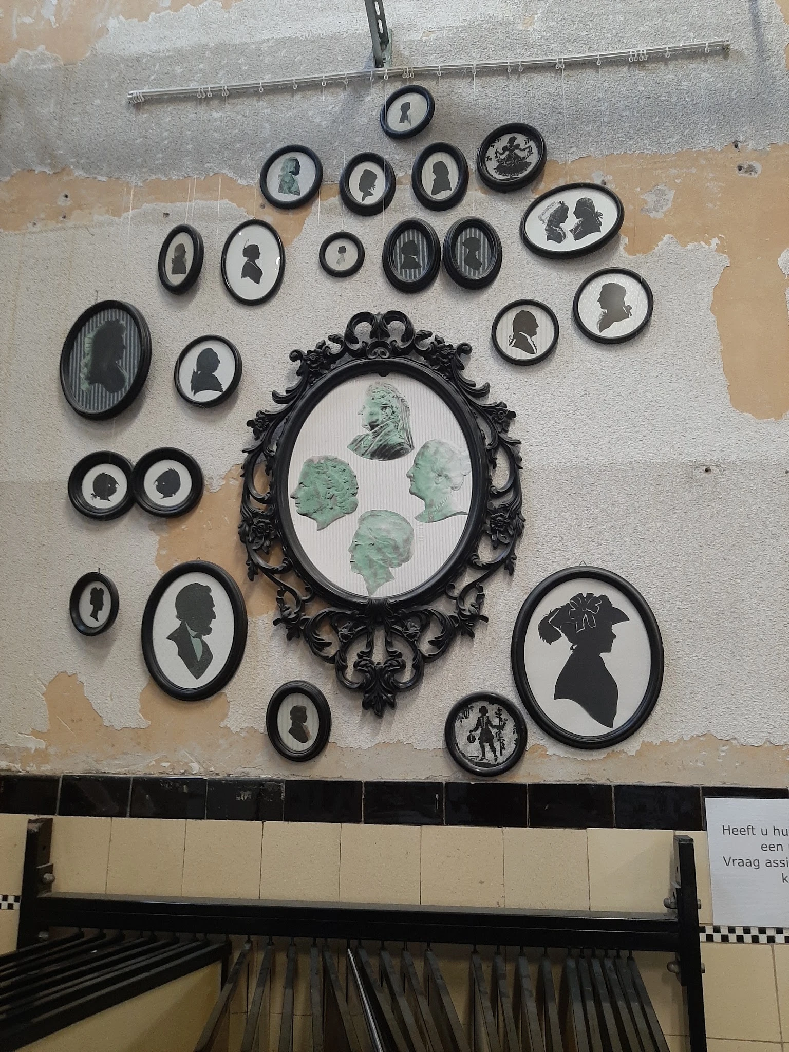 Verzameling zwarte ronde en ovale wanddecoraties met silhouetten en portretjes aan een witte muur