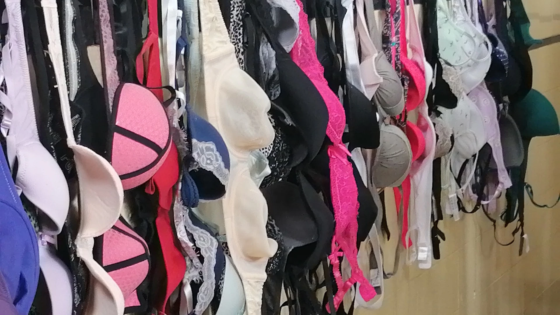 Rekken met tweedehands onderkleding in verschillende kleuren en maten, waaronder beha's in roze, zwart, wit en andere tinten