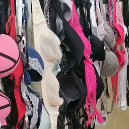 Rekken met tweedehands onderkleding in verschillende kleuren en maten, waaronder beha's in roze, zwart, wit en andere tinten