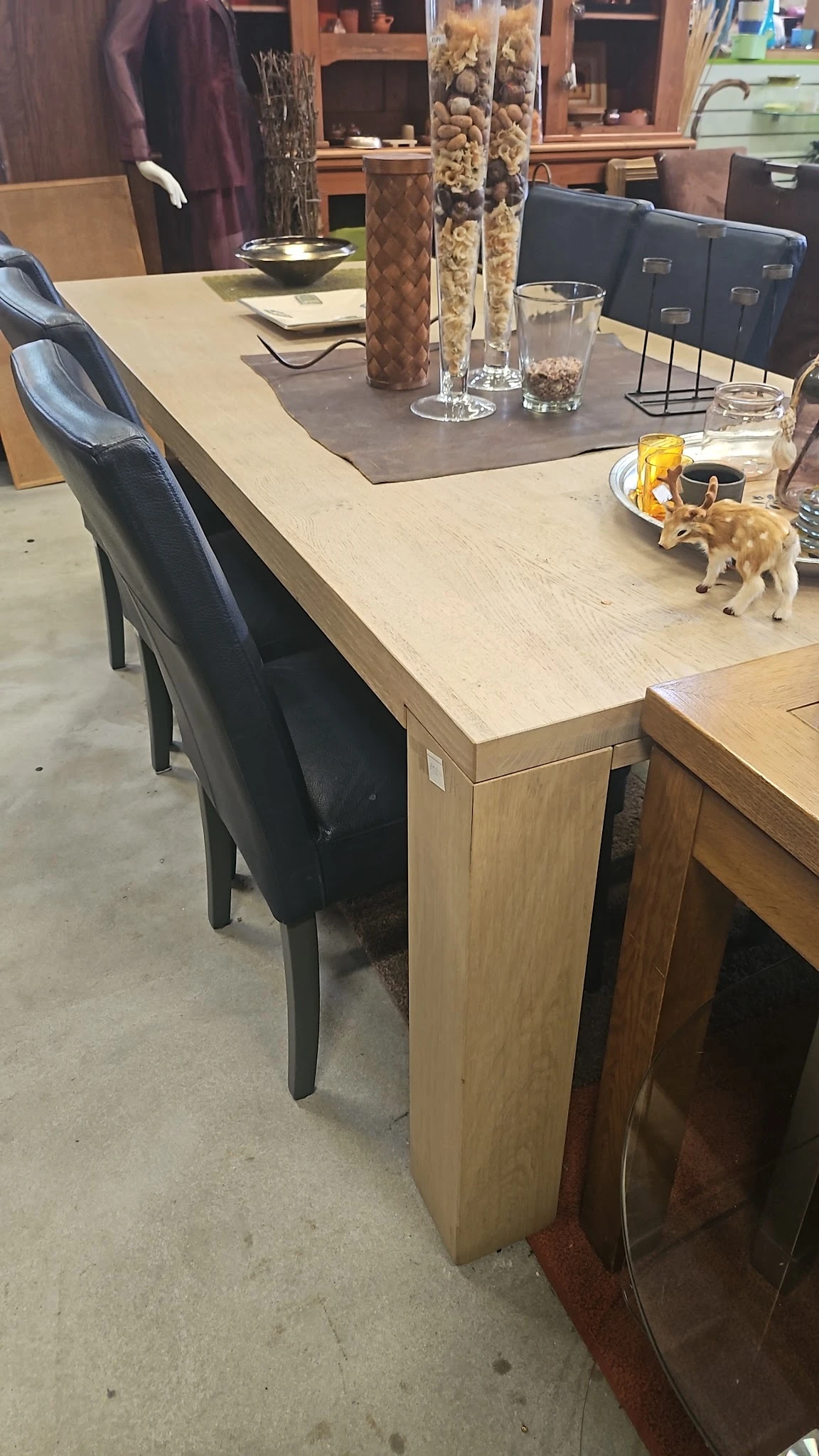 Houten tafel met zwarte stoelen in een winkelruimte, op het tafelblad staan diverse spullen