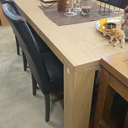 Houten tafel met zwarte stoelen in een winkelruimte, op het tafelblad staan diverse spullen