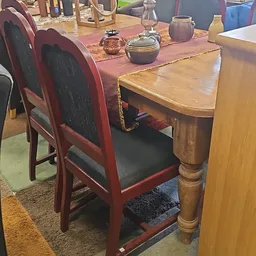Houten eettafel met rood geschilderde stoelen met zwarte zitting