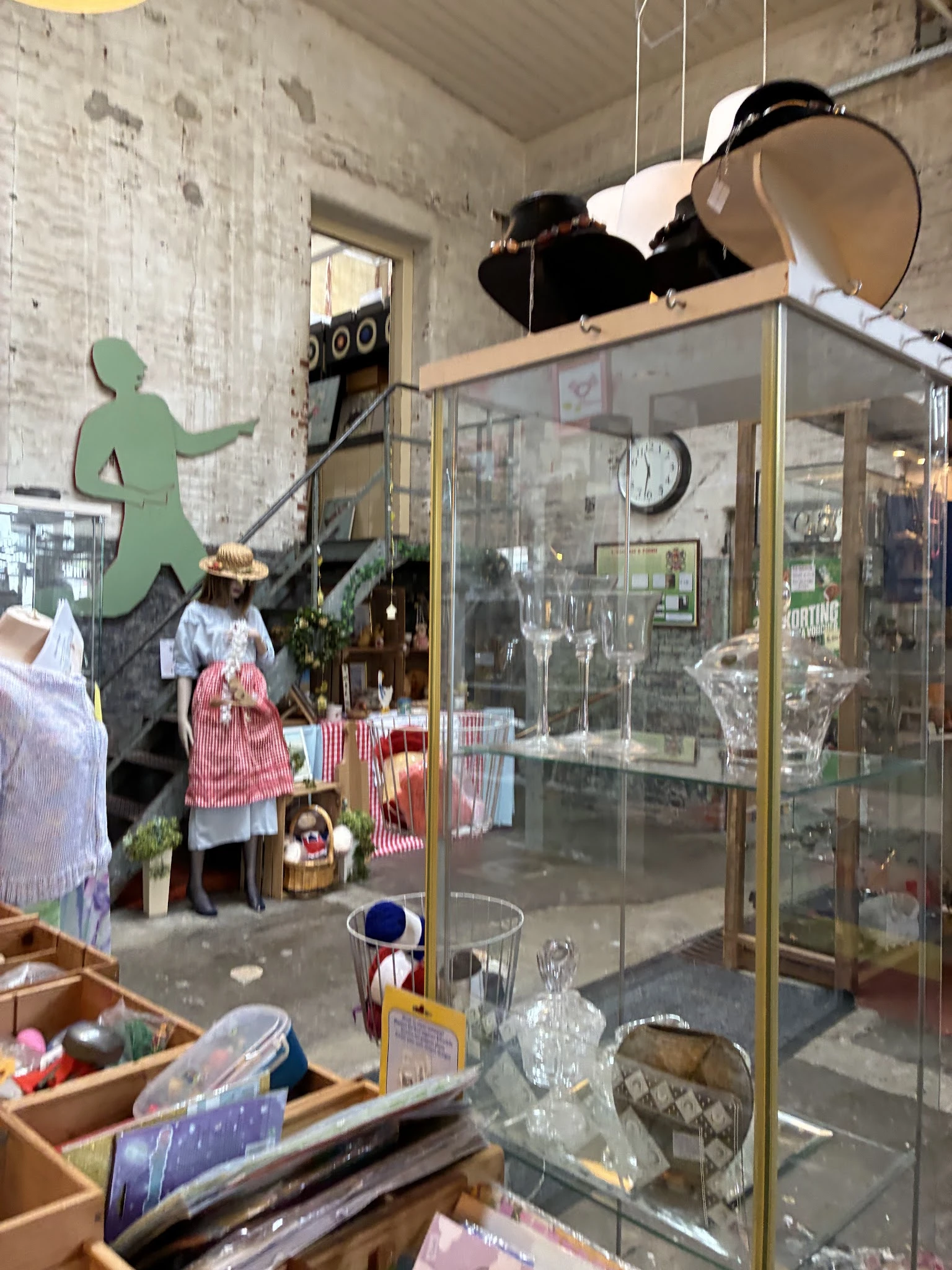 Winkelinterieur met vitrinekast, etalagepop in rood-wit gestreepte kleding en groene wandfiguur