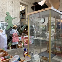 Winkelinterieur met vitrinekast, etalagepop in rood-wit gestreepte kleding en groene wandfiguur