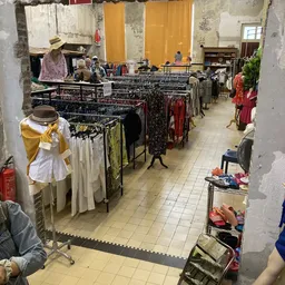 Winkelinterieur met rekken vol tweedehands kleding en mannequins met uitgestalde kledingstukken
