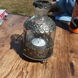 Decoratieve glazen fles met ornamentaal metalen montuur en brandende witte kaars erin
