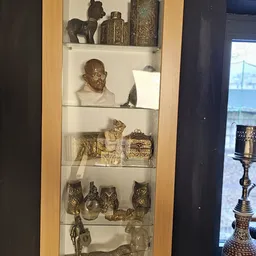 Glazen vitrinekast met bronzen beeldjes van uilen, een buste en decoratieve objecten