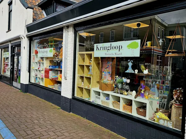 Winkelpui van Kringloop Hoeksche Waard met etalagevensters vol tweedehands spullen en groene stellingen