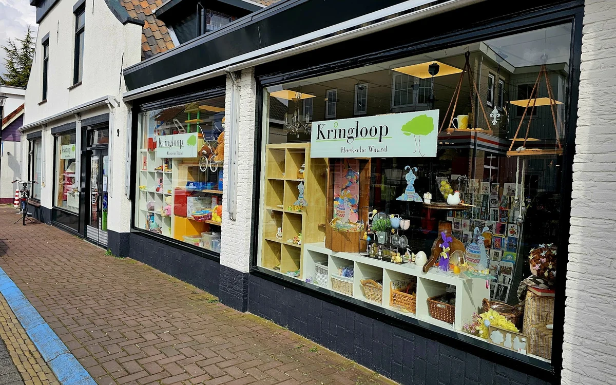 Winkelpui van Kringloop Hoeksche Waard met etalagevensters vol tweedehands spullen en groene stellingen