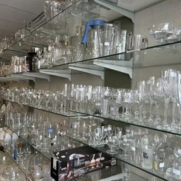 Glazen kasten met uitgestald glaswerk en kristallen servies in verschillende maten en vormen