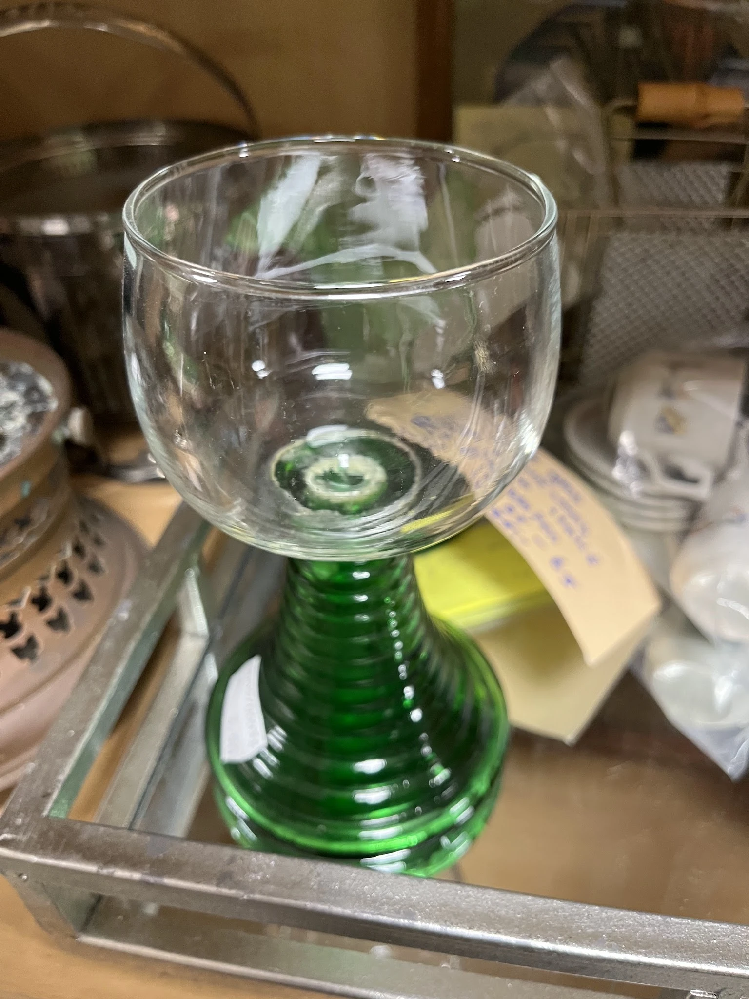 Groen glazen fles met glas erop in een kringloopwinkel