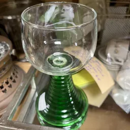 Groen glazen fles met glas erop in een kringloopwinkel