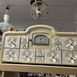 Vintage mengpaneel met meerdere draaiknoppen en centrale klok, gebruikt voor portieverdeling in een oud huishouden
