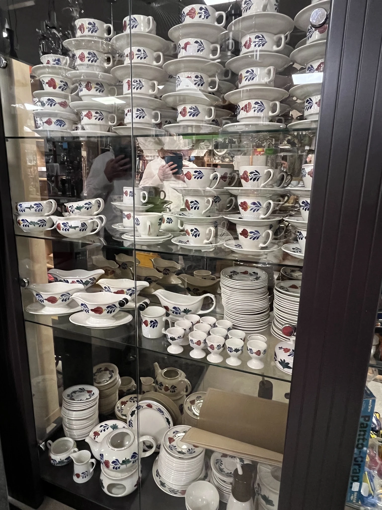 Glazen vitrine vol met serviesgoed: kopjes, schotels en borden met bloemenpatroon