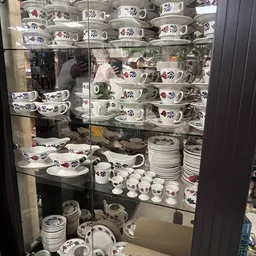 Glazen vitrine vol met serviesgoed: kopjes, schotels en borden met bloemenpatroon