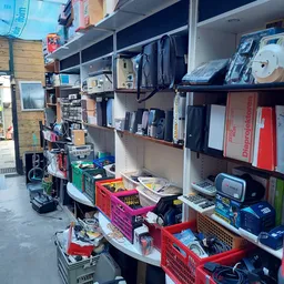 Stellingen met elektronische apparaten, huishoudelijke items en verschillende goederen in een kringloopwinkel