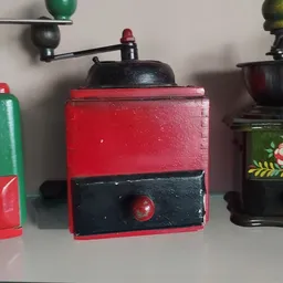 Rode en zwarte vintage koffiemolen met metalen bovenkant op display