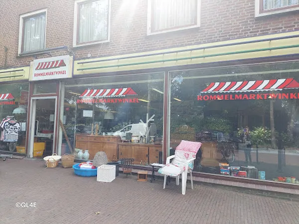 Winkelgevel met rood-wit gestreepte luifels en grote ramen, met daarvoor diverse spullen op het terras