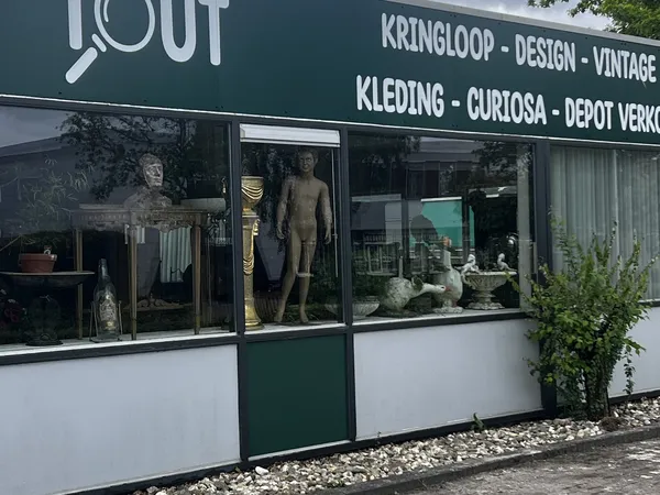 Winkelgevel met groene deur, witte en donkergroene pui, etalageruiten met beeldhouwerken en decoratieve objecten