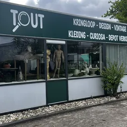 Winkelgevel met groene deur, witte en donkergroene puien, etalage met beelden en decoratieve objecten