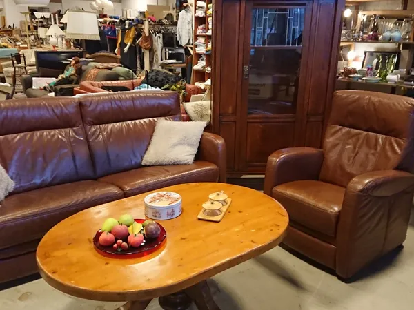 Zithoek met bruinleren meubels, houten tafel met fruit en decoraties, winkelvloer op achtergrond