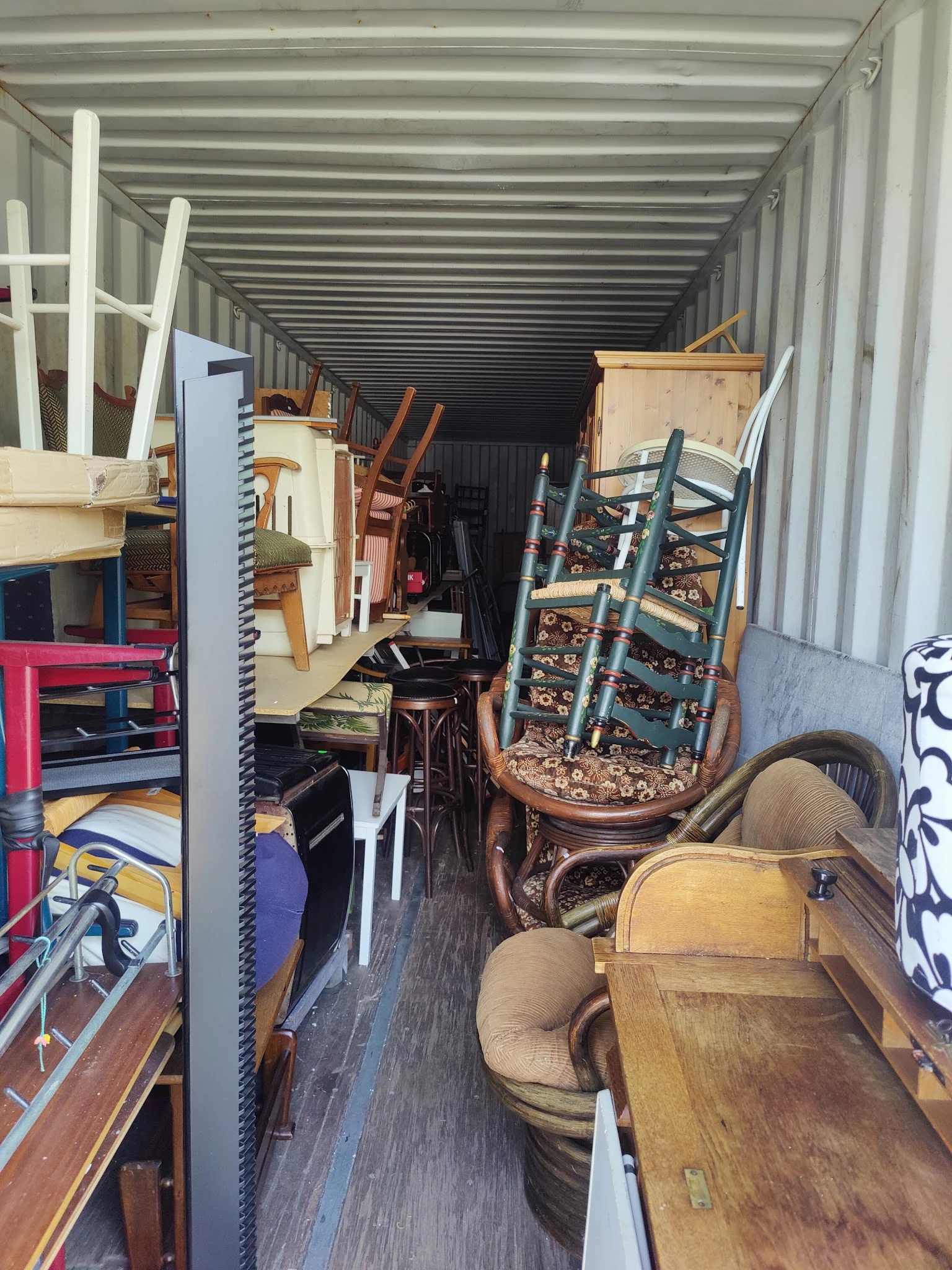 Volle opslagcontainer met diverse tweedehands meubelstukken en huishoudartikelen