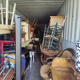 Volle opslagcontainer met diverse tweedehands meubelstukken en huishoudartikelen