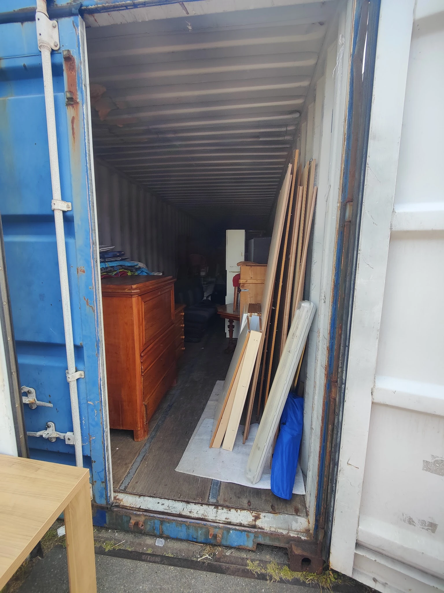 Binnenkant van een opslagcontainer met houten meubels en diverse spullen