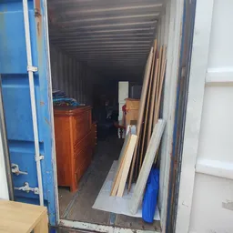 Binnenkant van een opslagcontainer met houten meubels en diverse spullen