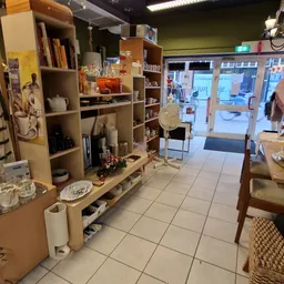 Winkelvloer van kringloopwinkel met houten stellingkasten, uitgestalde spullen en zicht op de ingang