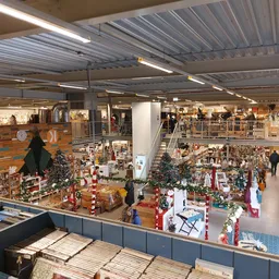 Overzicht van de kringloopwinkel met meerdere verdiepingen, tafels met kerstdecoraties en spullen, stellingen met artikelen e