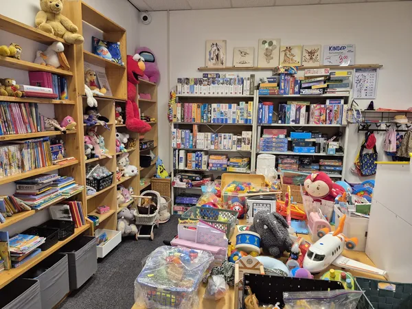 Rommelige winkelruimte vol speelgoed, boeken, poppen en verschillende voorwerpen op tafel en planken
