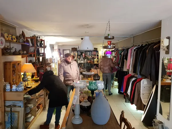 Winkelvloer van kringloopwinkel met kledingrekken, meubels, lampen en decoratieve items