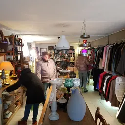 Winkelvloer van kringloopwinkel met kledingrekken, meubels, lampen en decoratieve items