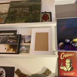 Wandplank met uitgestalde kunstwerken, foto's, schilderijen en een vintage koffiebord