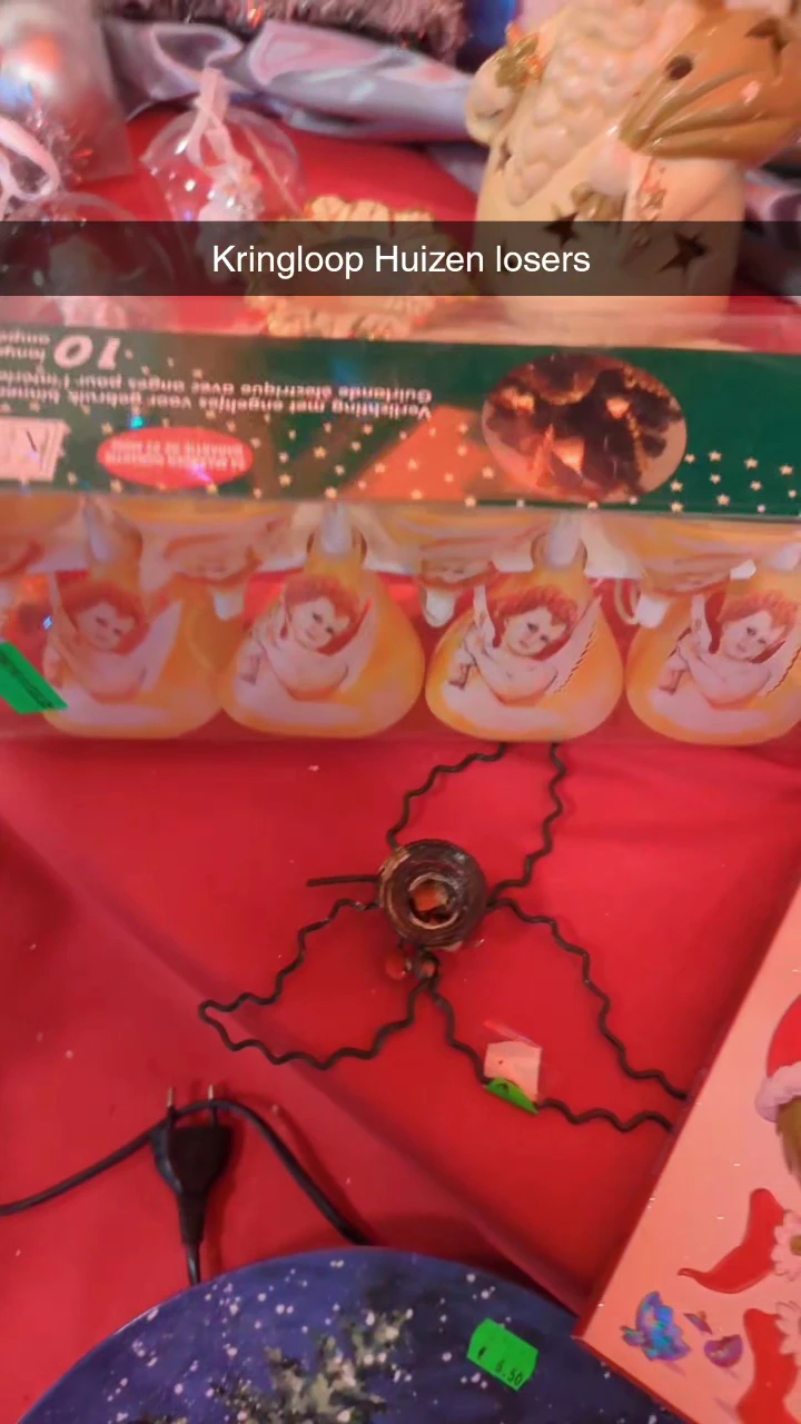 Oranje/rode speelgoedpoppen en een zwart speelgoedartikel op rode achtergrond in kringloopwinkel