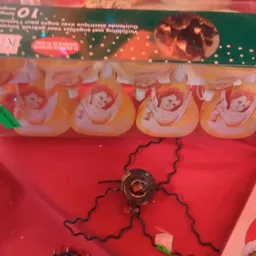 Oranje/rode speelgoedpoppen en een zwart speelgoedartikel op rode achtergrond in kringloopwinkel