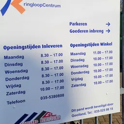 Openingstijden en contactgegevens van een kringloopwinkel op een informatiebord