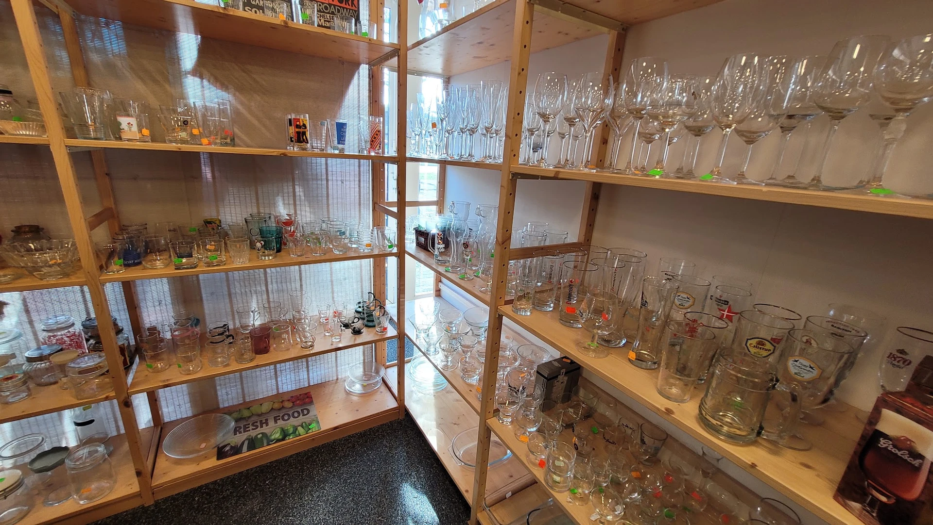 Glazen kasten vol met drinkglazen, wijnglazen en ander glaswerk uitgestald in de kringloopwinkel